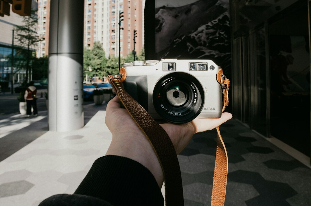 Chilean documentary photographer holding a camera on a city street